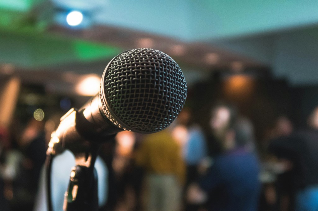 a mic in front of a distant crowd. kane-reinholdtsen-LETdkk7wHQk-unsplash